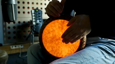 Slow motion hands of a percussionist playing solo darbouka rhythm, tomtom drum for percussion with a lamp installed in. 
