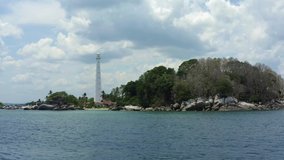 dramatic aerial view of light house with beautiful cloud in lengkuas island of belitung. drone backward flying, pullback shot. low flying