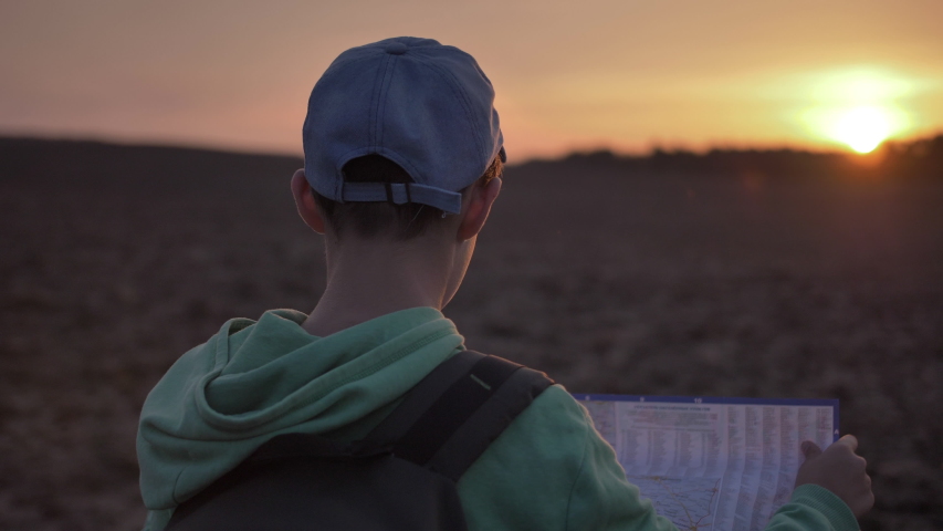 funny boy travel with a map at sunset outdoors, landmark