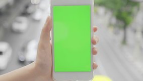 Hand holding telephone smart phone green screen chroma key traffic city blurred background