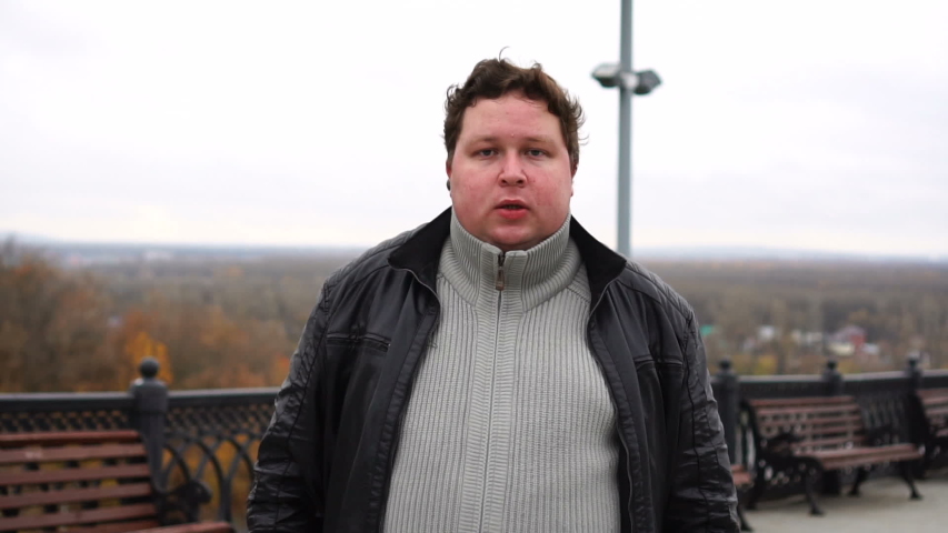 Portrait of fat man looking at camera and walking at city.