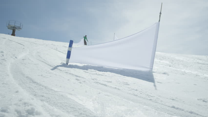 SLOW MOTION: Race snowboarder riding slalom between the gates