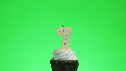 Lighting a number seven birthday candle on a delicious cup cake, green screen 7
