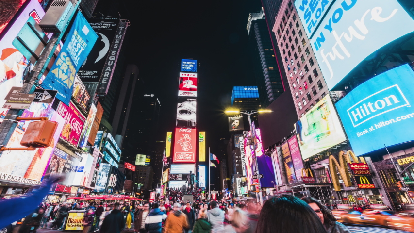 New York City, United States - Mar 31, 2019: Crowded people, car traffic transportation and billboards displaying advertisement at night in Times Square. American lifestyle or modern city life concept