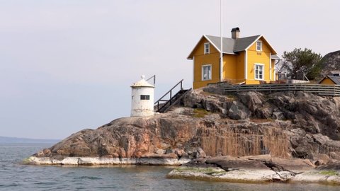 Traditional yellow Nordic house on a small cliff by the water sea