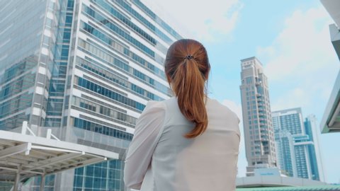 Business woman looking out while standing near modern Office Building. 4K Slow Motion Corporate Shot with Moving Around 360 Camera
