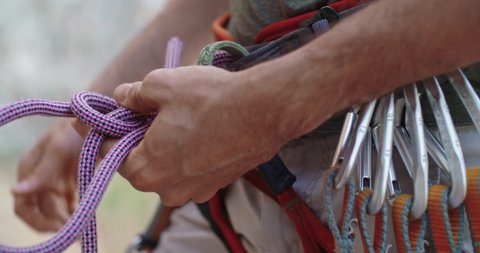 Climber man preparing for climbing up the rocky wall rift by checking rope. Climbing extreme active sport activity. Active people, outdoor activities.Rope detail shot.Slow motion 4k video.