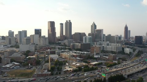 4K Ariel Drone Shot Over Skyline Buildings In Atlanta, Georgia. USA. Pretty Tall Skyline Over Tree Area and Busy Highway Road With Cars Driving Through. Important Tall Buildings, Sunny Blue Skies 