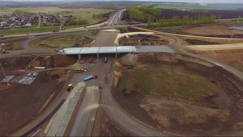Aerial view construction of a new highway. A drone takes off over a construction site with workers and specialized road equipment