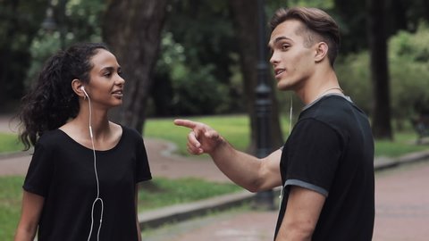 Young Handsome Man Gesturing Giving Directions to Preety Musline Girl In the Park.