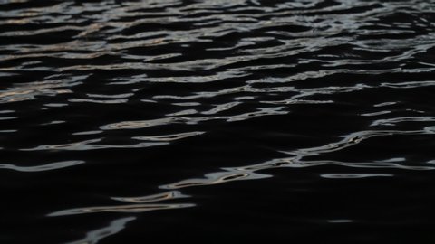 Slow motion of water ripples at sunset. Abstract scene of contrast colors movement, black blue golden and silver. Trapiche, San Luis, Argentina