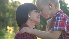 happy family funny video slow motion play music teamwork outdoors. Mom and son lifestyle listen to music on smartphone in same headphones for two. happy family woman mother and little boy son spend