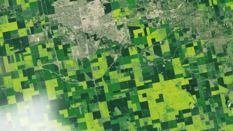 Large agricutural green field pattern canola plant oil production in Canada and Regina city aerial satellite view. Contains public domain image by Nasa