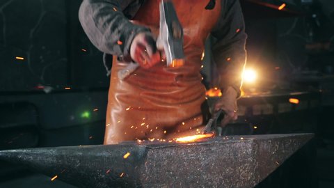 Blacksmith is using hammer to forge metal