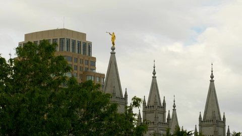 A distant view of the Salt Lake City Temple located in Utah. The angel Moroni is seen in with clouds in the back ground.