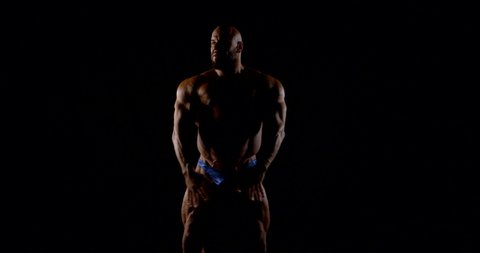 brutal muscular bald bearded male bodybuilder close-up on a black background, he poses, shows muscles.