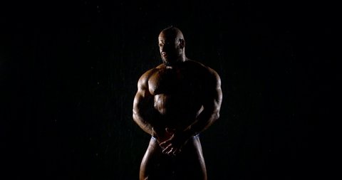 brutal muscular bald bearded male bodybuilder close-up on a black background, he poses, shows biceps.