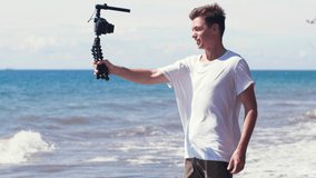Young male vlogger filming travel story on the beach.