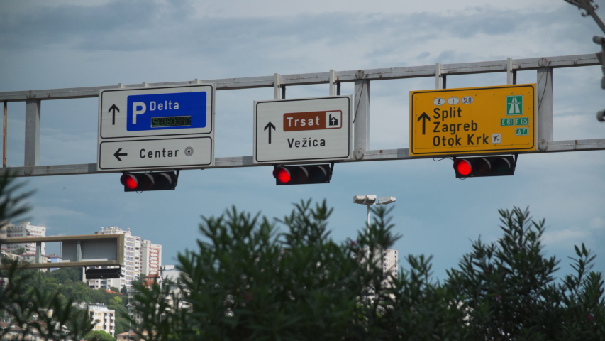 Traffic signals and Signs over roadway in Rijeka Croatia, trees and buildings, Handheld