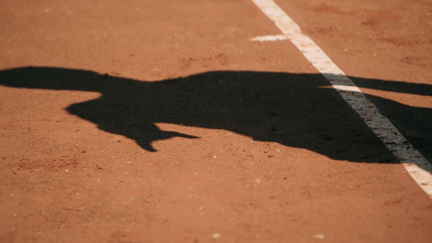 Shadow of tennis player bouncing ball on clay court and serving. Royalty-Free Stock Footage #1039563263