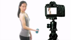 Asian teenage girl lifting dumbbell, seen through camera, vlogger concept