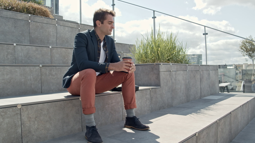 Lockdown Wide Shot Of Handsome Man Sitting On Step Outside And Drinking From Disposable Coffee Cup