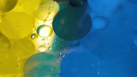 Psychedelic blue and yellow oil and water abstract background. Abstract colorful 4K video. Foam of Soap with Bubbles macro shot.Closeup bubbles in water. Oil drops on a water surface blue and yellow