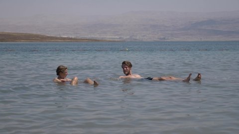 Dead Sea, Israel - Sep 19, 2019: People are bathing and swimming in the Dead Sea. The salinity of the dead sea water makes people floating in water. Dead sea is located between Jordan and Israel.