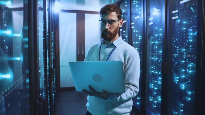 Caucasian IT engineer in modern data center using laptop inspecting working high tech computer server racks. Concept of cybersecurity, database and digital information. - Powered by Shutterstock - Get 15% off with code: PIKWIZARD15