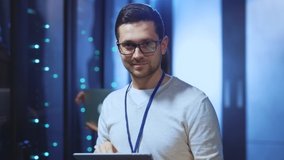 Positive IT administrator running diagnostics on tablet checking server rack system quality maintenance in modern data center. Portrait of cheerful smiling young engineer. - Powered by Shutterstock - Get 15% off with code: PIKWIZARD15