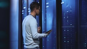 Caucasian IT administrator opening server rack cabinet monitoring system performance using digital tablet working in huge technology data storage center. - Powered by Shutterstock - Get 15% off with code: PIKWIZARD15
