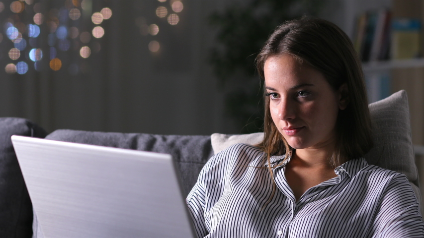 Serious woman using a laptop working sitting on a couch in the night at home Royalty-Free Stock Footage #1039589714