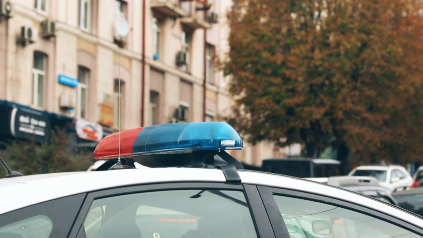 Police car with flasher close-up get stuck and moving slow through city road with car traffic jam during rush hour time. Many vehicles on street