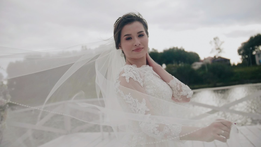 A beautiful girl in a snow-white dress with a long veil. The veil develops in the wind. Beautiful scenery
