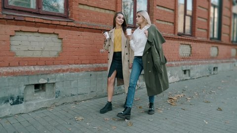 Happy pretty girls are walking around the city together. Teen friends are talking and laughing outdoor