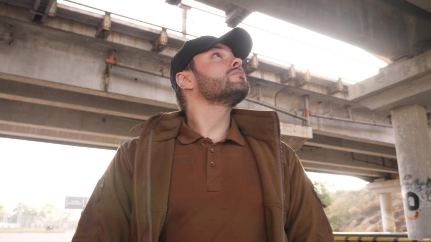 Dangerous man in hood walks under bridge