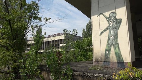 Chernobyl zone, Ukraine - 8th of August 2019: 4K Visit to Pripyat Ghost Town - Old culture palace and a target picture on the wall with shell holes on it, "Energetic culture palace" written in Russian