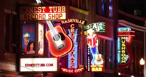 Nashville, Tennessee - June 20, 2019: Colorful neon store signs hang along the bars restaurants and record stores along Broadway Street in downtown Nashville Tennessee USA