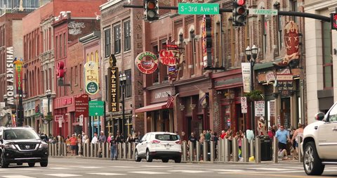 Nashville, Tennessee - June 20, 2019: People walk along the businesses and bars on Broadway in Nashville Tennessee USA. Broadway is known for its honky-tonks, Music and record stores.