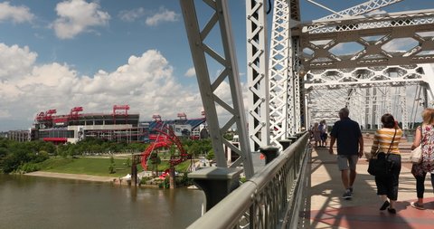 Nashville, Tennessee - June 20, 2019: People cross the John Seigenthaler Pedestrian Bridge in Nashville Tennessee USA. The bridge is pedestrian-only over the Cumberland River