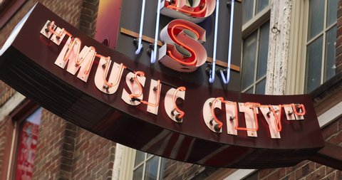 Colorful music city neon store signs hang along the bars restaurants and record stores along Broadway Street in downtown Nashville Tennessee USA