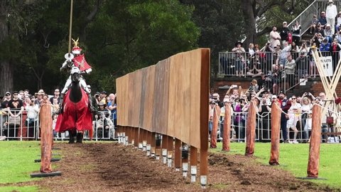 St Ives Showground, Sydney, Australia - Sept 21 2019: Knights in sliver armour on war horses charge at each other in a jousting tournament at St Ives Medieval Faire breaking their lances