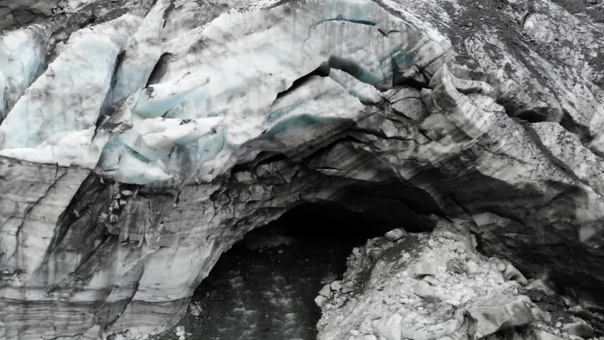 Aerial - Ice cave collapsing from a glacier on a river, with water splashing