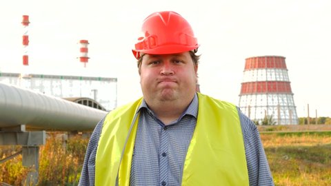 Funny worker, engineer, or electrician looking directly at the camera and mimicking grimacing and showing his tongue like a clown in front of a power station. Employee of the year