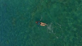 Vertical video. Aerial shot of a woman snorkeling in a beautiful turquoise sea