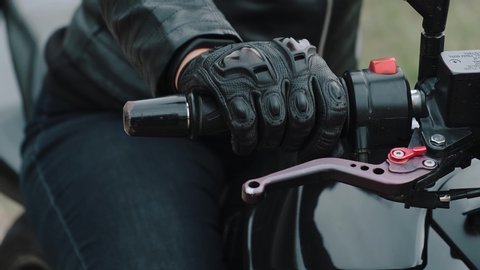Close-up of the Motorcyclist's Hand. The concept of speed, movement, breakthrough, acceleration. A female hand in a leather glove turns the throttle on a motorcycle.