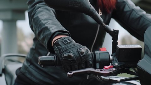Close-up of the Motorcyclist's Hand. The concept of speed, movement, breakthrough, acceleration. A female hand in a leather glove turns the throttle on a motorcycle.
