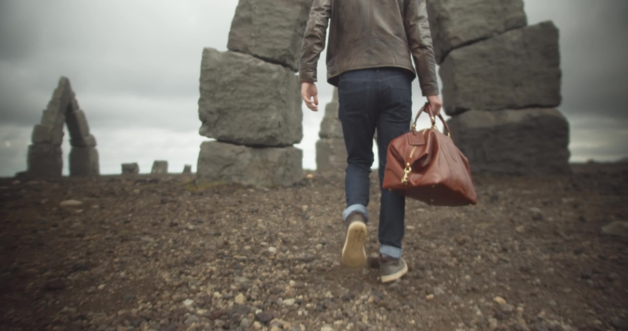 A man carries his brown bag through the archway of The Arctic Henge in Iceland
