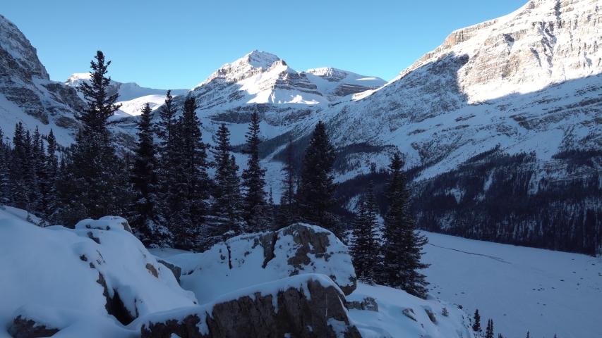 Hiker take a small break and sit down to enjoy the beautiful wide view to the snowy forest and mountains of Jasper National Park in Canada.