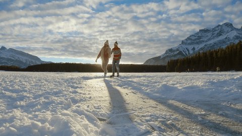 Young couple ice skating in winter outdoors on a frozen lake in Canada